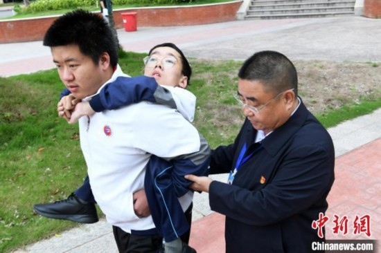 朱金祥背著鐘華強(qiáng)去教室上課的路上，也經(jīng)常碰到值班的校領(lǐng)導(dǎo)和老師前來搭把手。 卓忠偉 攝