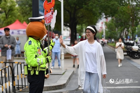 6月7日上午9時(shí)，隨著鈴聲的響起，2023年江西高考正式開考，江西省的53.57萬考生以縣（區(qū)）為單位隨機(jī)安排在全省256個(gè)考點(diǎn)、18968個(gè)考場參加高考。圖為“小熊交警”和考生擊掌鼓勵(lì)。 人民網(wǎng)記者 時(shí)雨攝