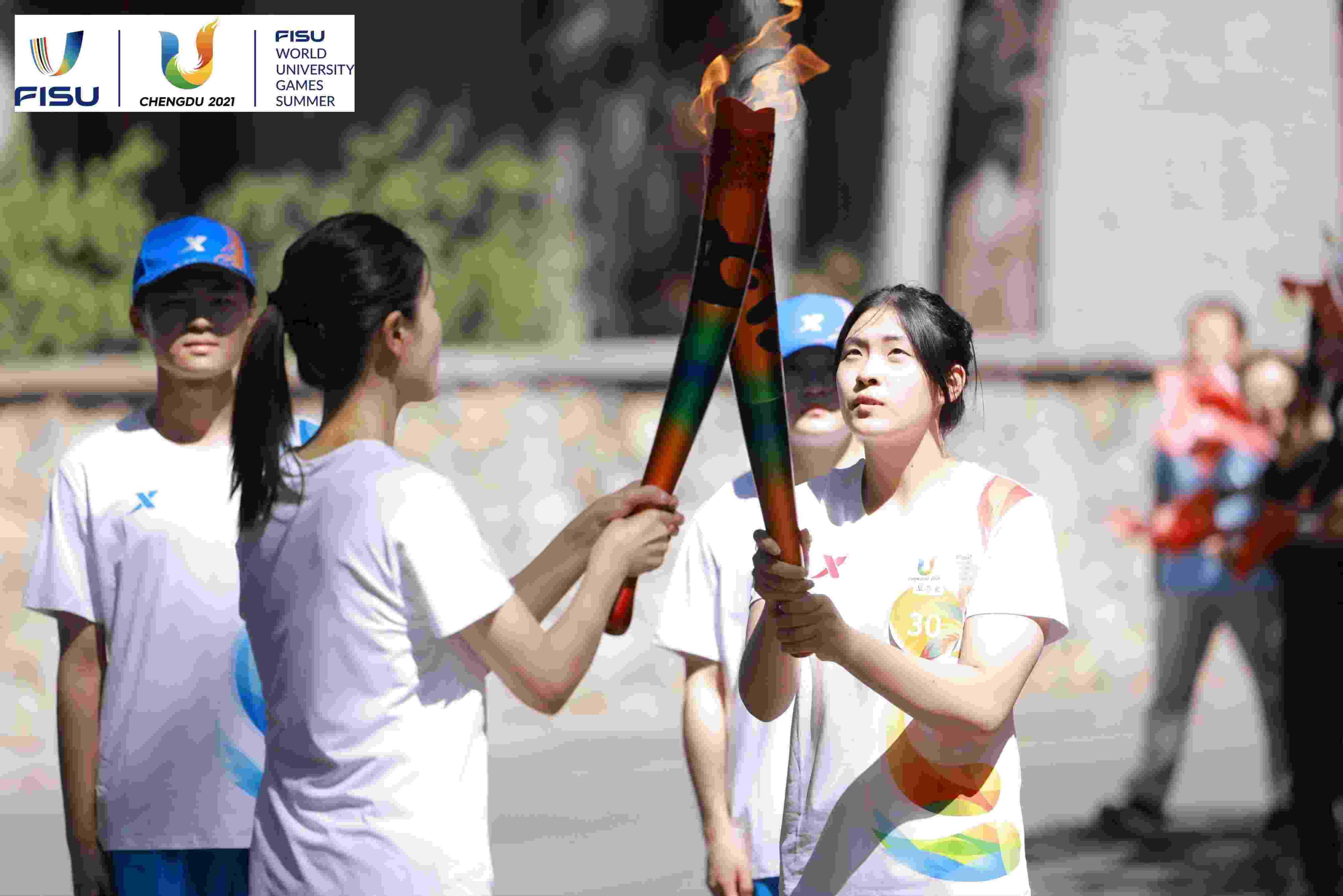 兩名大運(yùn)會(huì)火炬手進(jìn)行火炬?zhèn)鬟f。 圖片來源：成都大運(yùn)會(huì)執(zhí)委會(huì)供圖