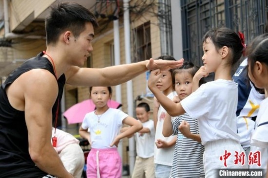 圖為大學(xué)生志愿者在組織孩子們參加體育健身活動(dòng)。廖光福 攝