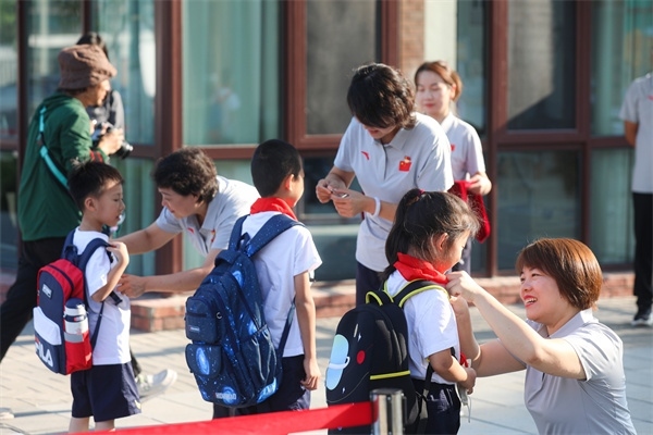 8月30日，雄安史家胡同小學(xué)學(xué)生體驗(yàn)學(xué)校生活。老師為學(xué)生佩戴?；?。