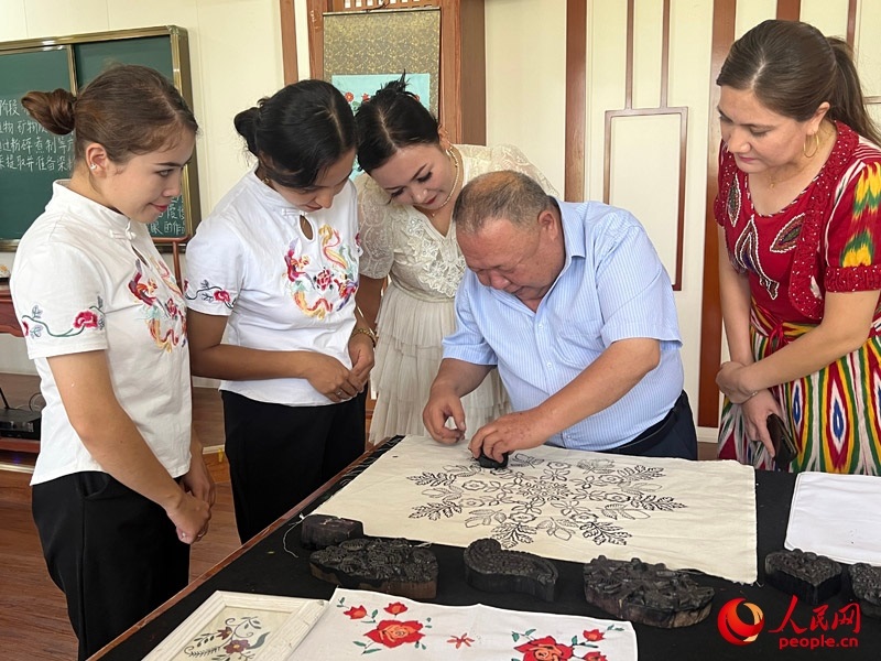 國(guó)家級(jí)非物質(zhì)文化遺產(chǎn)模戳印花布技藝傳承人吾吉阿西木?吾舒爾展示模戳印花布的制作過程。人民網(wǎng)記者 常雪梅攝