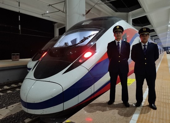 劉銀能（右一）與中國師父鄔俊鴻在動車組前合影。受訪者供圖