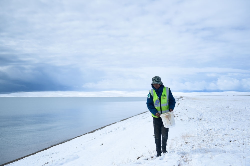 2021年10月20日，在青海省果洛藏族自治州瑪多縣扎陵湖鄉(xiāng)勒那村，三江源國家公園黃河源園區(qū)生態(tài)管護員在扎陵湖邊撿拾垃圾。新華社記者 張龍 攝