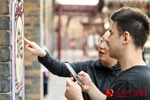 選手安德烈（俄羅斯）在老師指導(dǎo)下學(xué)習(xí)墻壁上張貼的生僻字。人民網(wǎng) 盧鵬宇攝