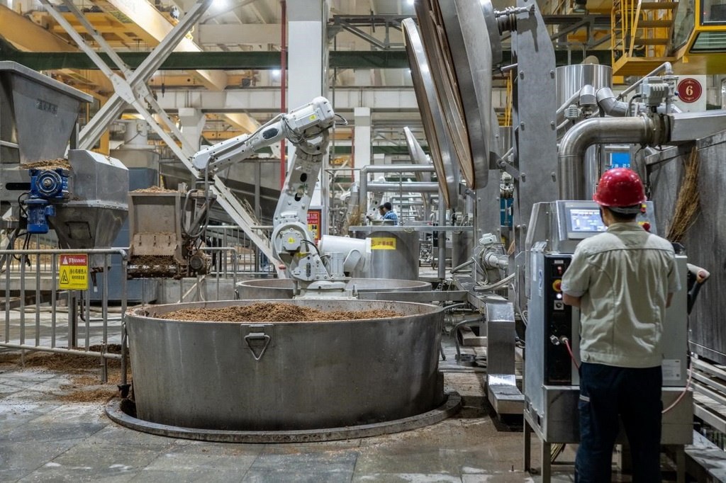 907車間里，機械臂正在撒料裝甑。嚴磊攝