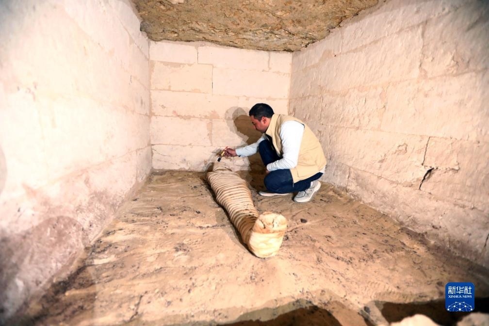 10月15日，在埃及明亞省考古現(xiàn)場，考古人員清理一座石鑿墓中的木乃伊。新華社發(fā)（艾哈邁德·戈馬攝）