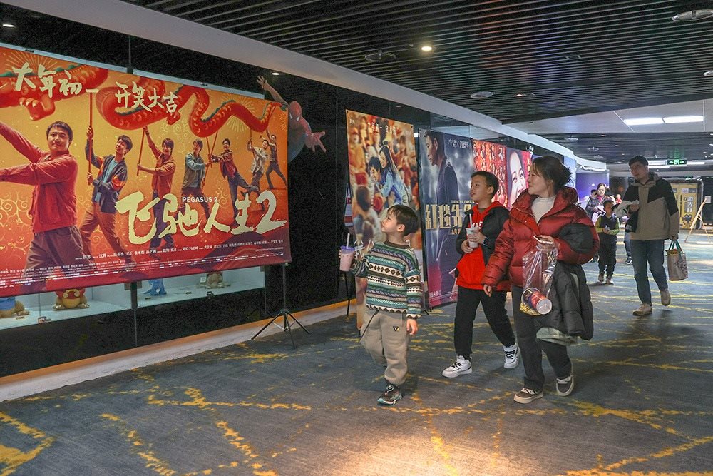 △ 2024年2月16日，在江西贛州一家電影院，觀眾從春節(jié)檔電影的宣傳展板前走過(guò)。