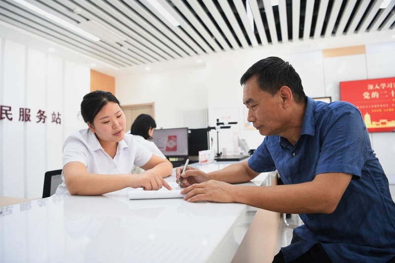 2023年5月23日，河北雄安新區(qū)容東片區(qū)南文營社區(qū)居民（右）在社區(qū)便民服務(wù)站辦理業(yè)務(wù)。