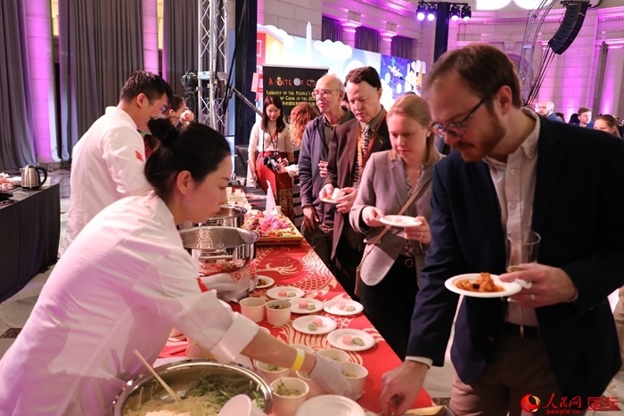 當(dāng)?shù)貢r(shí)間3月7日晚，華盛頓聯(lián)合車站廣場(chǎng)舉行駐美使團(tuán)“使館主廚挑戰(zhàn)賽”。圖為當(dāng)?shù)孛癖娫谥袊?guó)展臺(tái)前體驗(yàn)中國(guó)美食。人民網(wǎng)記者 李志偉攝