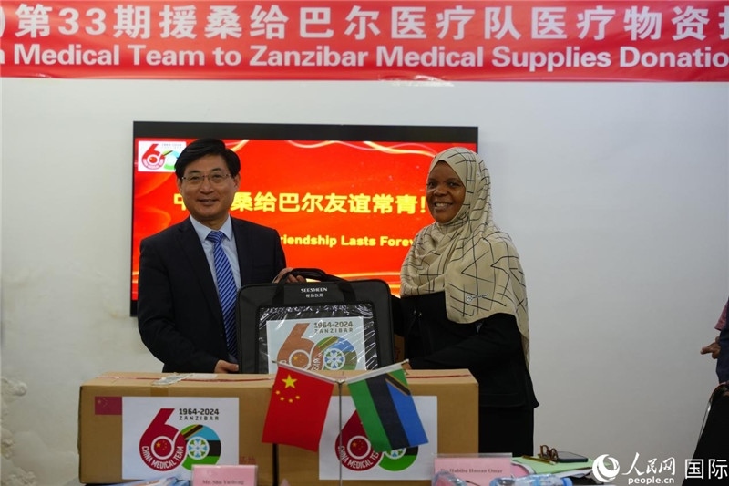 江蘇省蘇北人民醫(yī)院黨委書記束余聲捐贈(zèng)物資與桑衛(wèi)生部首席秘書哈比巴。中國(guó)援桑醫(yī)療隊(duì)供圖