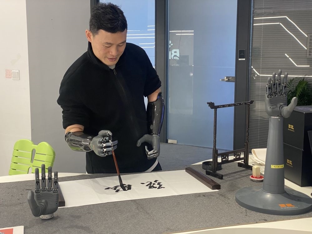 2024年3月29日，在浙江強(qiáng)腦科技有限公司展廳內(nèi)，失去雙手的產(chǎn)品體驗(yàn)官倪敏成依靠智能仿生手寫毛筆字。新華社記者 魏一駿 攝