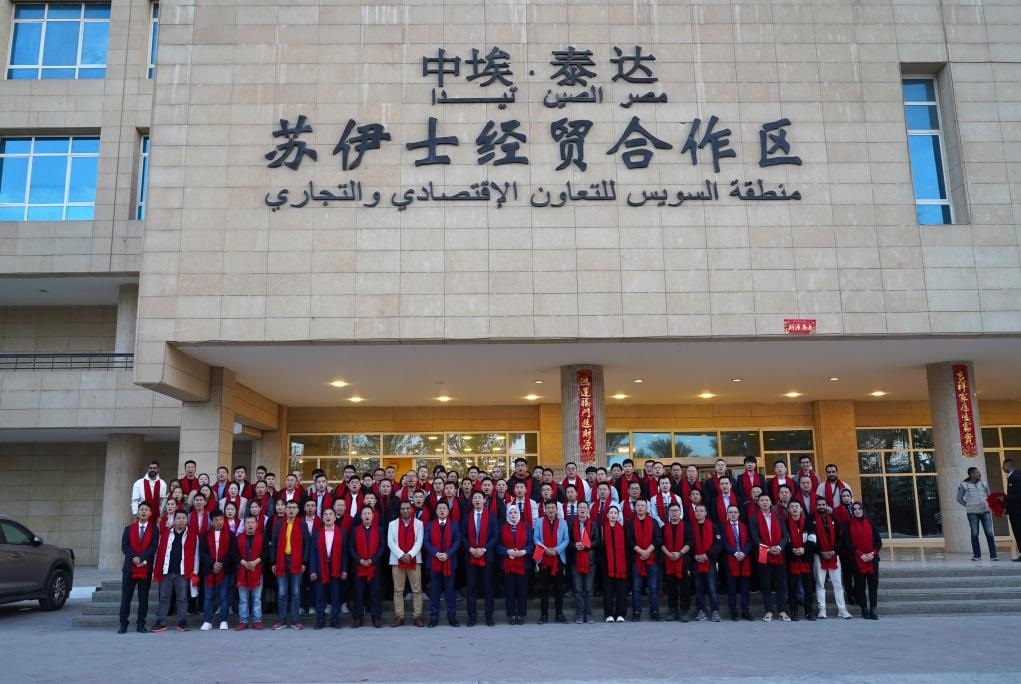 2024年2月11日，在位于埃及蘇伊士省的中?！ぬ┻_(dá)蘇伊士經(jīng)貿(mào)合作區(qū)，中埃員工在合作區(qū)辦公大樓前合影拜年。新華社發(fā)（泰達(dá)合作區(qū)供圖）