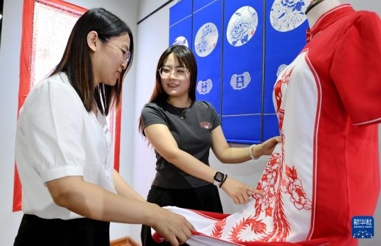 5月31日，在衡水市阜城縣一家剪紙工作室，游客在觀賞帶有剪紙元素的旗袍。