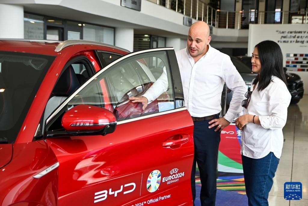 2024年5月29日，在馬耳他比爾基卡拉，馬耳他哈桑-扎米特汽車公司首席執(zhí)行官德古阿拉（左）介紹一輛比亞迪純電動汽車。新華社發(fā)（喬納森·博格 攝）