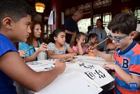 7月4日，在馬耳他桑塔露琪亞市的中國(guó)古典園林“靜園”，人們體驗(yàn)中國(guó)書(shū)法。新華社發(fā)（喬納森·博格 攝）