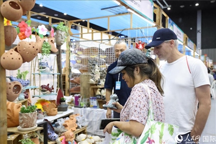 游客在蘭納博覽會(huì)特色展位上選購(gòu)工藝品。人民網(wǎng)記者楊一攝