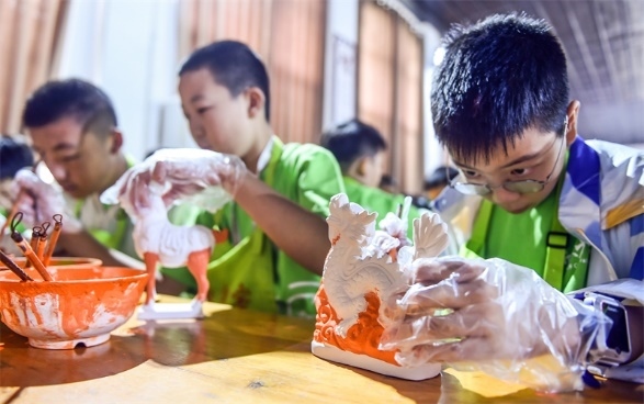 小朋友們在洛陽市孟津區(qū)朝陽鎮(zhèn)南石山村體驗唐三彩素胎施釉技藝。圖片來源：視覺中國