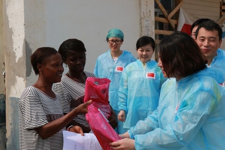 2015年4月4日，在位于塞拉利昂首都弗里敦市郊的中塞友好醫(yī)院埃博拉診療中心，中國(guó)第四批援塞醫(yī)療隊(duì)副隊(duì)長(zhǎng)邵蔚（右前）向被治愈的埃博拉出血熱患者贈(zèng)送禮物。新華社發(fā)（祖榮強(qiáng) 攝）