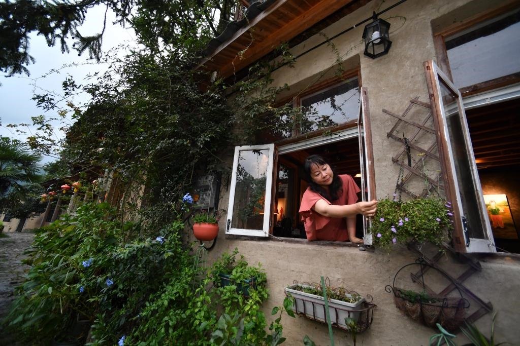 8月29日，在福建省屏南縣熙嶺鄉(xiāng)，龍?zhí)洞濉靶麓迕瘛泵泛暝诖蚶碜约航?jīng)營(yíng)的民宿外墻裝飾花盆。新華社記者姜克紅 攝