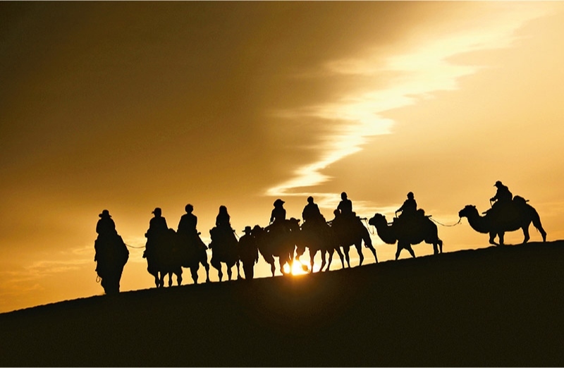 新時代以來，文化和旅游深度融合發(fā)展體制機(jī)制不斷健全，成功走出了一條獨(dú)具特色的中國旅游發(fā)展之路。圖為2024年9月1日清晨，游客在甘肅省敦煌市鳴沙山月牙泉景區(qū)乘騎駱駝，欣賞大漠風(fēng)光，體驗絲路風(fēng)情。 新華社發(fā) 張曉亮/攝