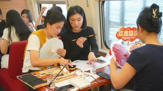 10月1日，旅客們?cè)贕1634次列車上給油紙傘作畫。新華社記者周義 攝