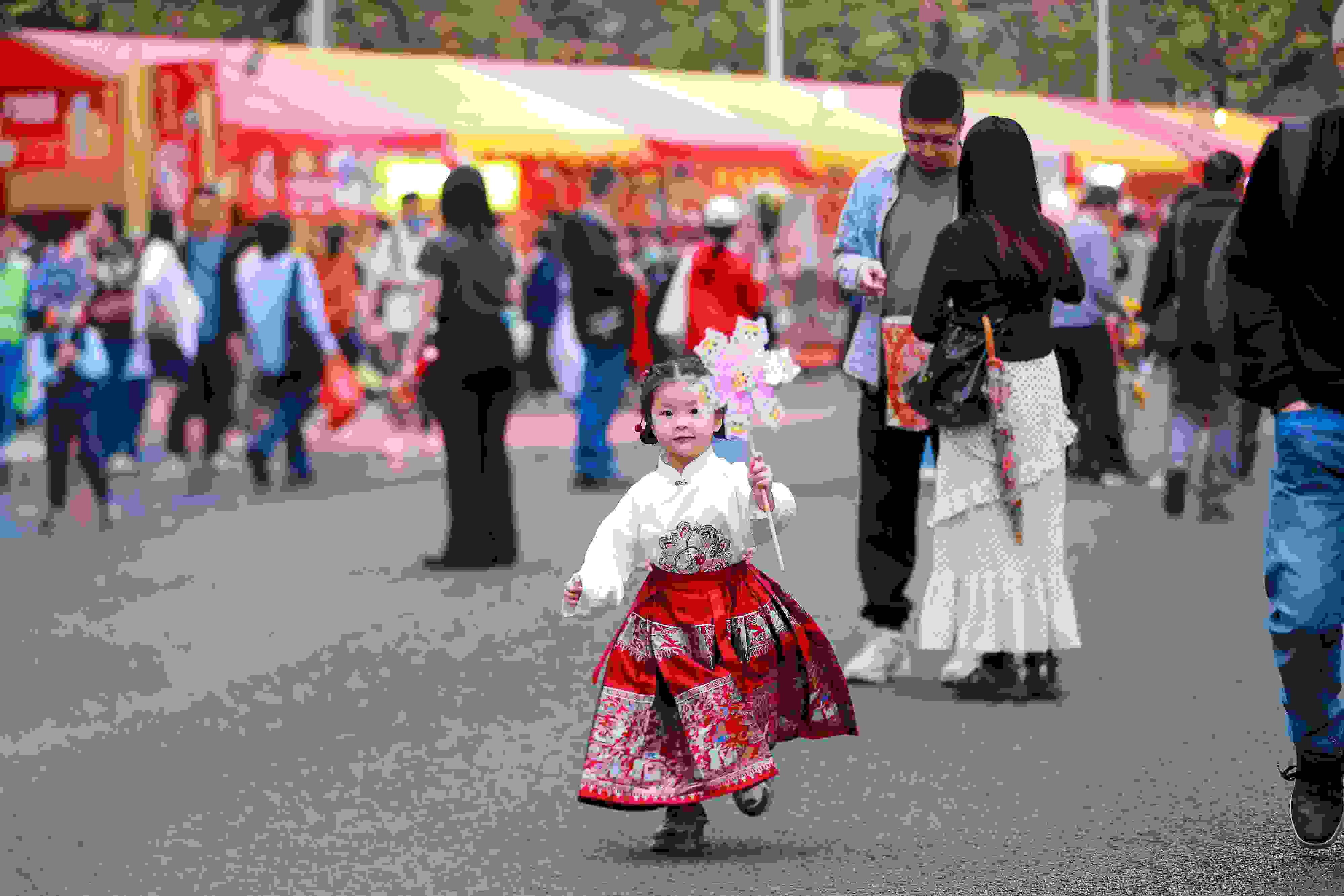 拿著風車穿著馬面裙的小女孩在廣州的花市上開心奔跑。