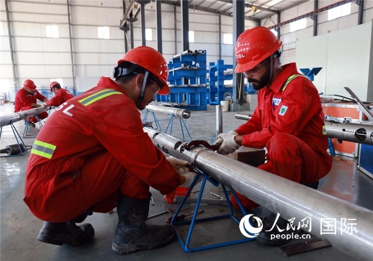 中伊員工共同在檢修鉆井設(shè)備。人民網(wǎng)記者管克江攝