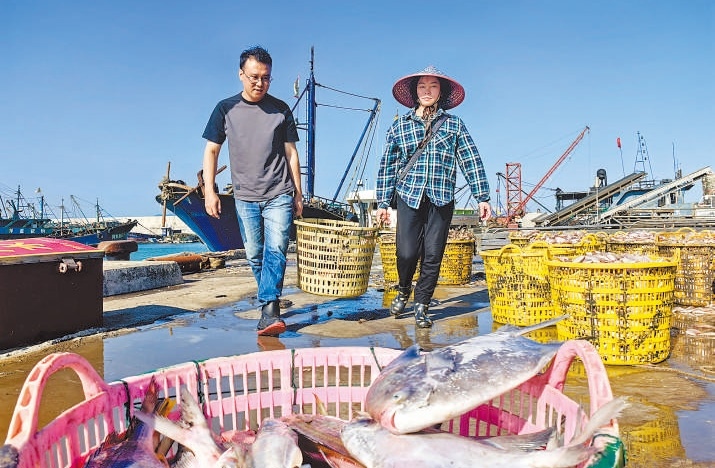 許小斌（左）和漁民一起搬運(yùn)海鮮。本報記者 付 文攝