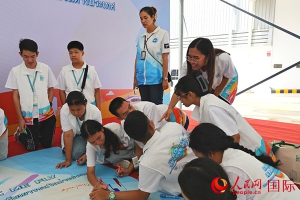 泰國學生在開營儀式展板上繪制圖案。人民網(wǎng)記者 白元琪攝