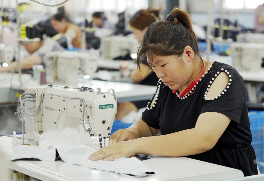 5月20日，村民在李寨村服裝加工廠內(nèi)忙碌。河南省周口市沈丘縣馮營鎮(zhèn)李寨村地處豫東平原。近年來，乘著脫貧攻堅與鄉(xiāng)村振興政策的東風(fēng)，李寨村積極探索產(chǎn)業(yè)發(fā)展模式，通過“龍頭企業(yè)+村集體經(jīng)濟+農(nóng)戶”的方式，逐漸發(fā)展形成肉牛養(yǎng)殖、設(shè)施農(nóng)業(yè)、服裝加工、康養(yǎng)民宿等產(chǎn)業(yè)，以產(chǎn)業(yè)振興助力鄉(xiāng)村振興。新華社記者 李嘉南 攝