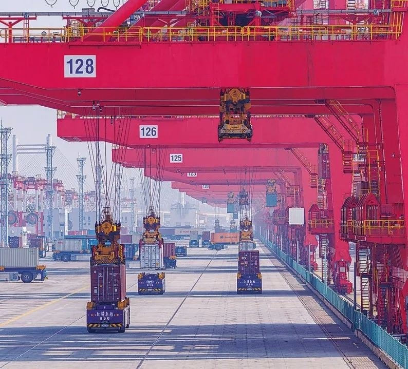 共建“一帶一路”國家在工作制度對接、技術標準協(xié)調(diào)、檢驗結果互認等方面強化合作、統(tǒng)一標準，貿(mào)易自由化便利化水平不斷提升。上海洋山港海關對接共建國家進出口貨物相關標準，推動通關一體化方式申報，提升通關效率。圖為無人駕駛的全自動導引車在洋山港穿梭往來，搬運集裝箱。王初 攝