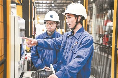 在廣西柳工機械股份有限公司生產(chǎn)車間內(nèi)，一名高級技師（右）給徒弟講解數(shù)控設(shè)備操作細(xì)節(jié)。新華社記者 曹祎銘攝