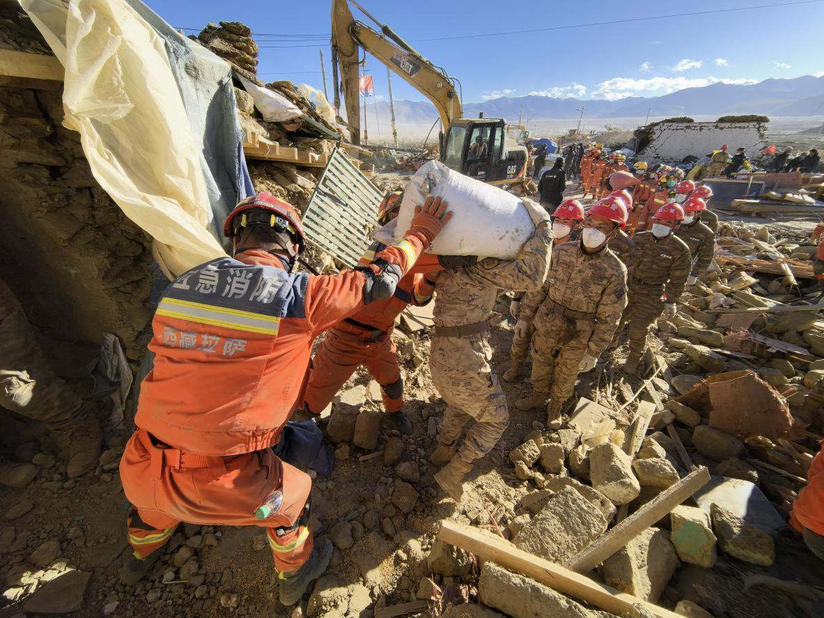 1月11日，定日縣長(zhǎng)所鄉(xiāng)古榮村，應(yīng)急消防等救援人員排隊(duì)接力搶運(yùn)掩埋在倒塌房屋下的群眾財(cái)物。人民日?qǐng)?bào)記者楊翹楚攝