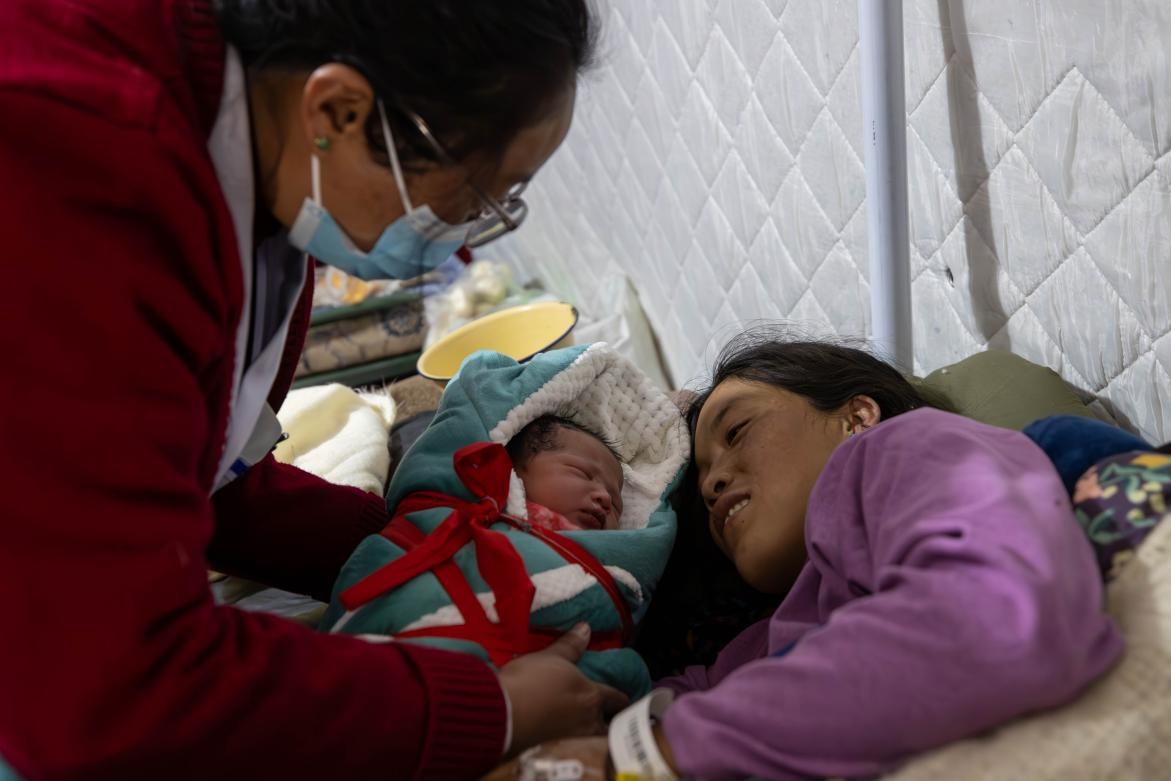 1月10日，定日縣中心醫(yī)院的婦產(chǎn)科醫(yī)生悉心照看一位母親和她懷里的新生兒。人民日?qǐng)?bào)記者張武軍攝