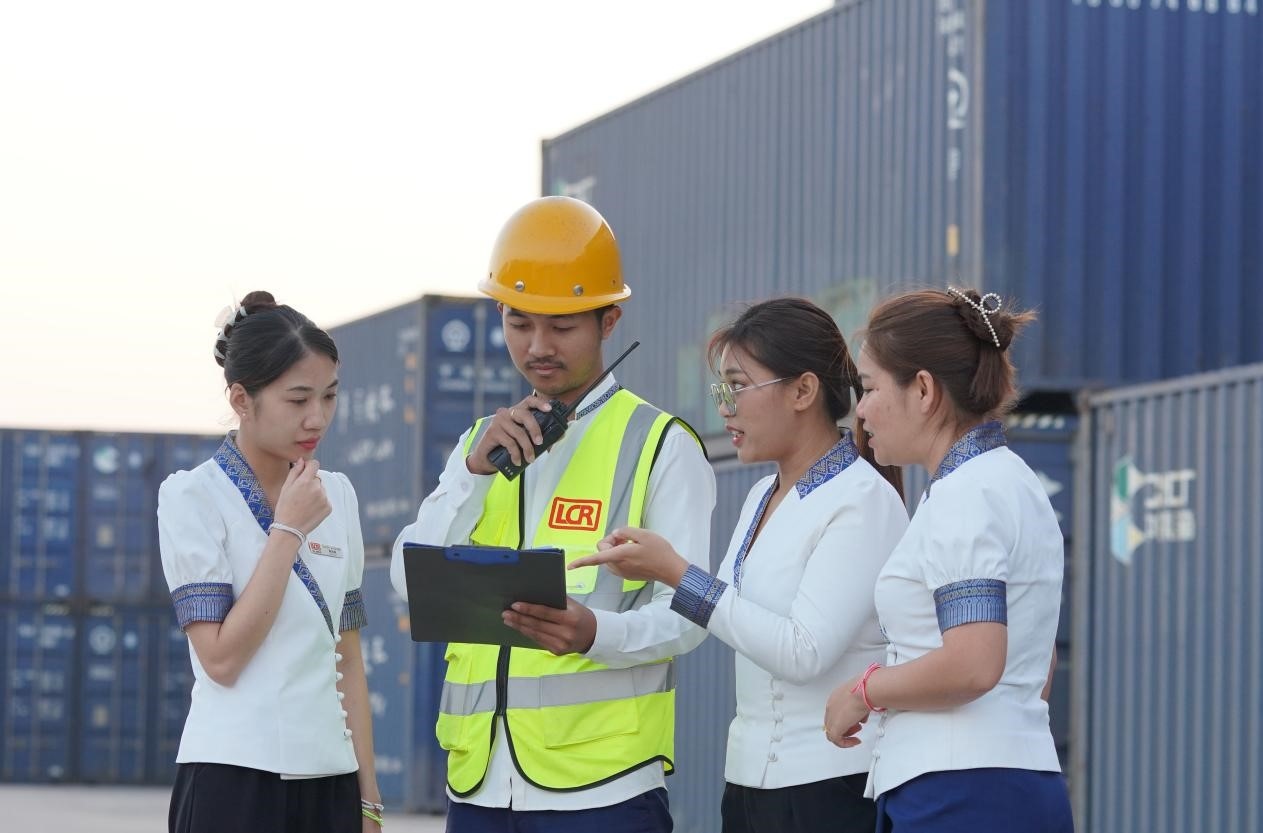 萬象南站貨運值班員陳尼啦（左一）與同事在一起討論工作。老中鐵路有限公司供圖