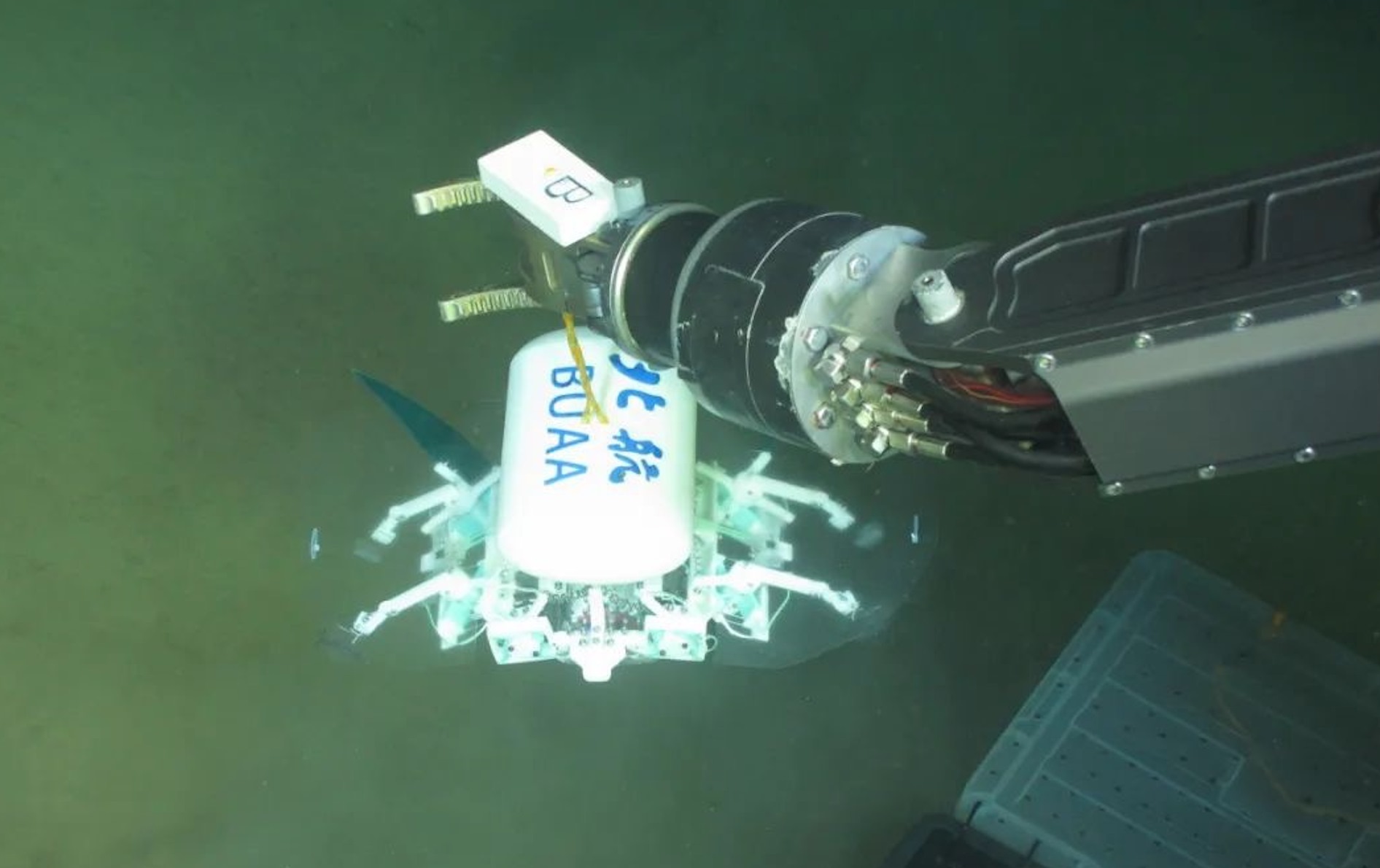 科研人員利用機械臂將北航深海小型機器人投于馬里亞納海溝。校方供圖