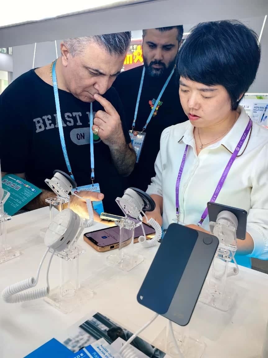 展臺(tái)工作人員向外商展示“AI TOP翻譯終端”。圖片來(lái)源：受訪者提供